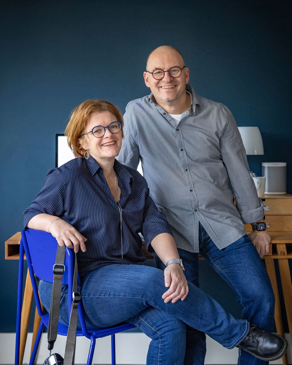 Nicolet and Guillaume Groen in front of a desk and a blue wall, smiling and relaxed.