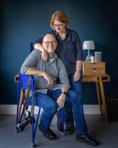 Guillaume and Nicolet Groen in a room with a blue wall and wooden desk.