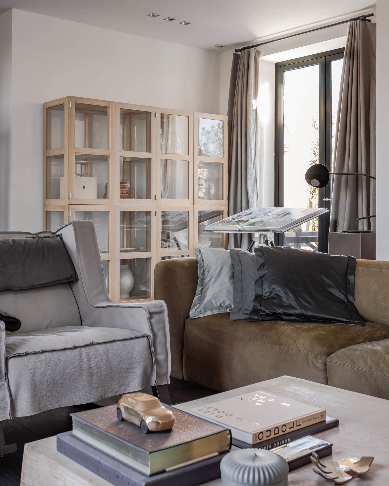 Living room with a greenish sofa, a gray armchair, and natural accessories.