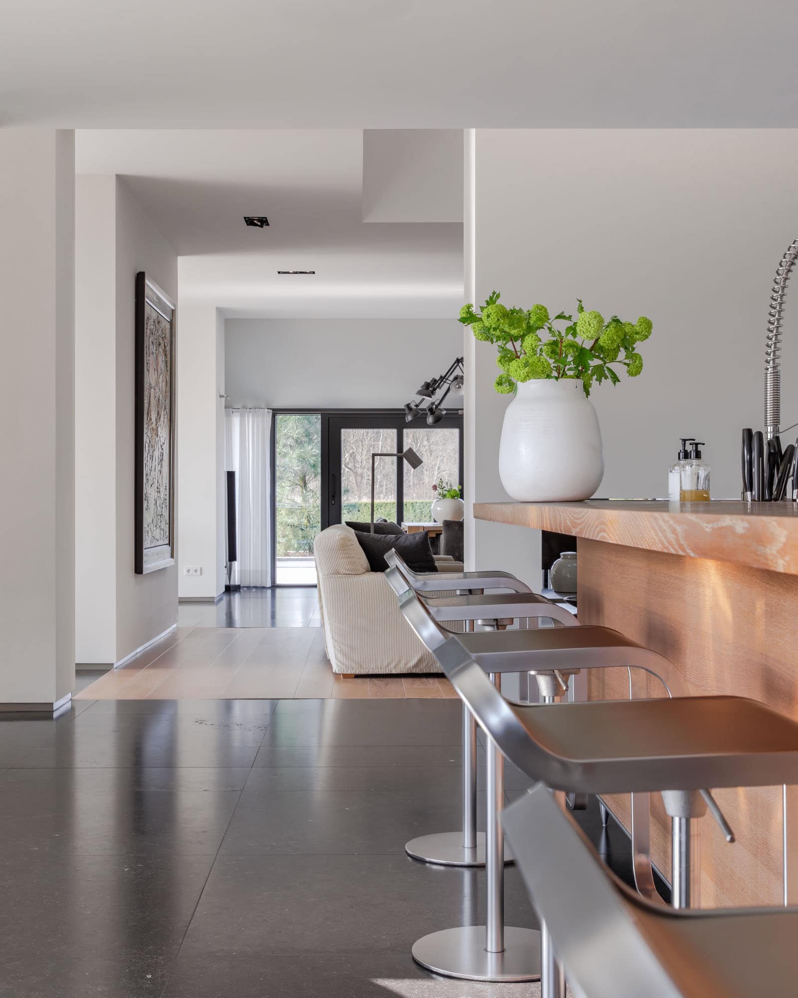 Bar stools at the kitchen counter in the back the living room with cream colored armchairs