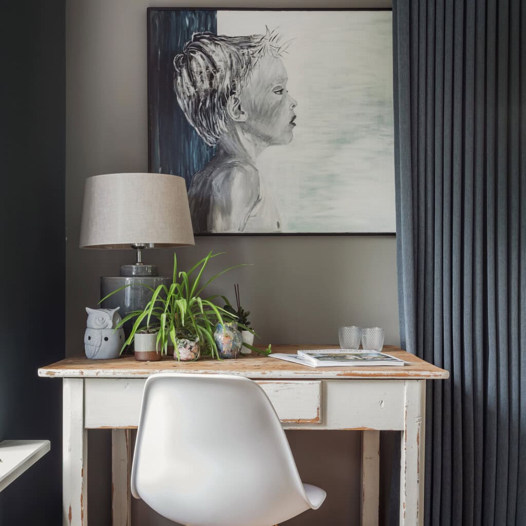 Vintage writing desk with an Eames chair and a blue-toned painting of a little boy.